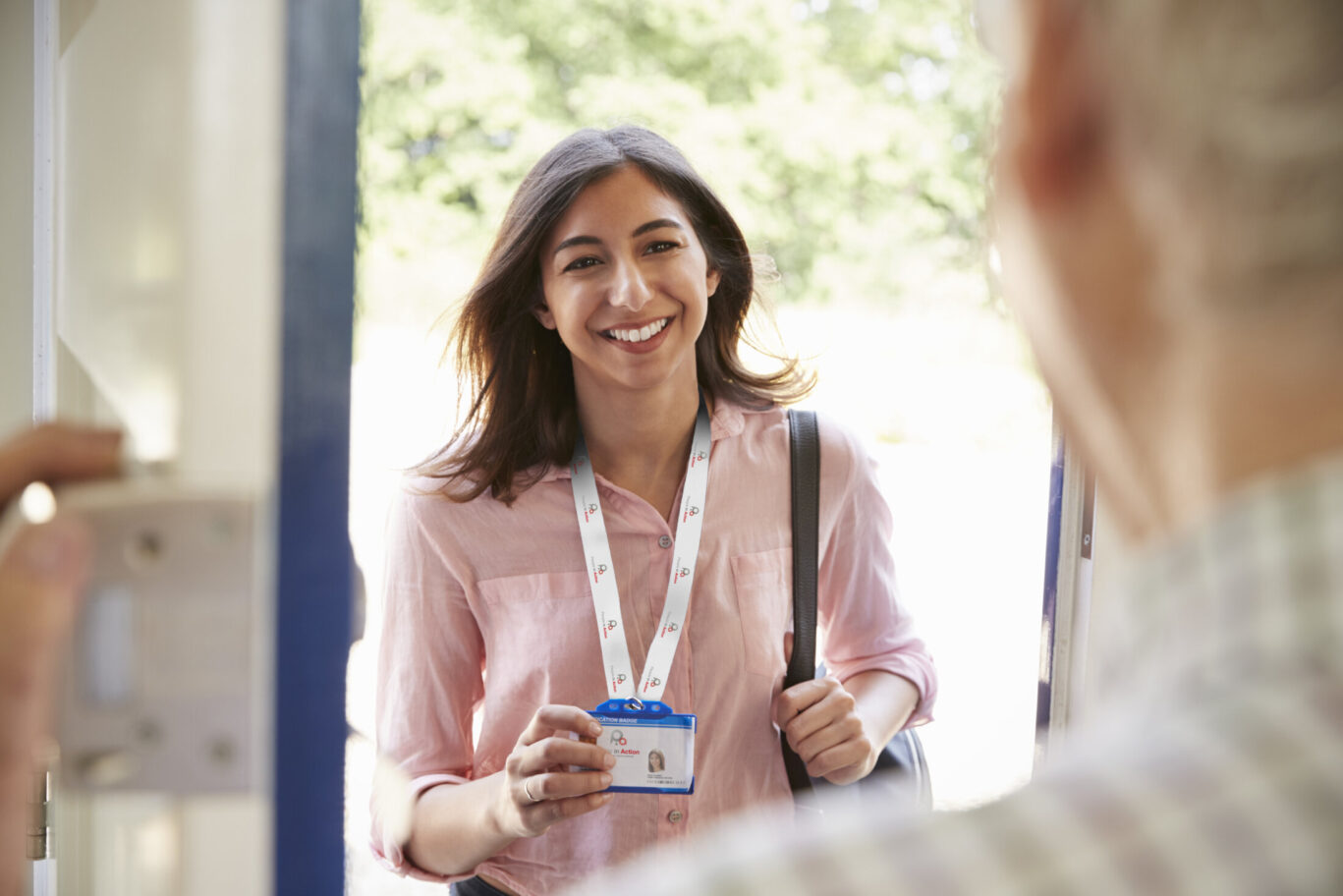 Senior man opening front door to young woman showing ID card