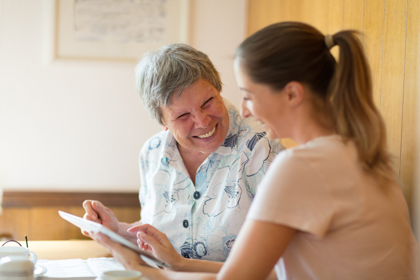 caregiver showing digital tablet to senior woman